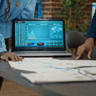 Coworkers examining reports on papers, looking at statistics and annual data analytics to increase profit. Workers group planning research strategy with documents for business development.