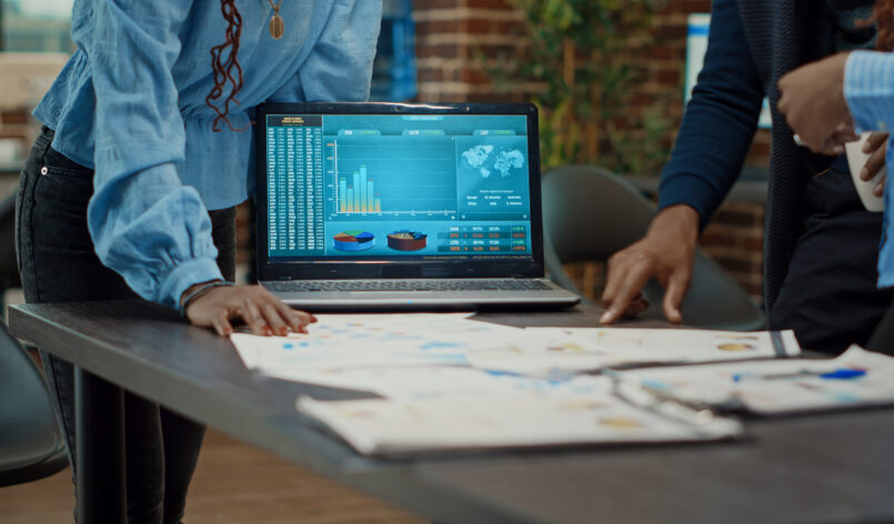 Coworkers examining reports on papers, looking at statistics and annual data analytics to increase profit. Workers group planning research strategy with documents for business development.